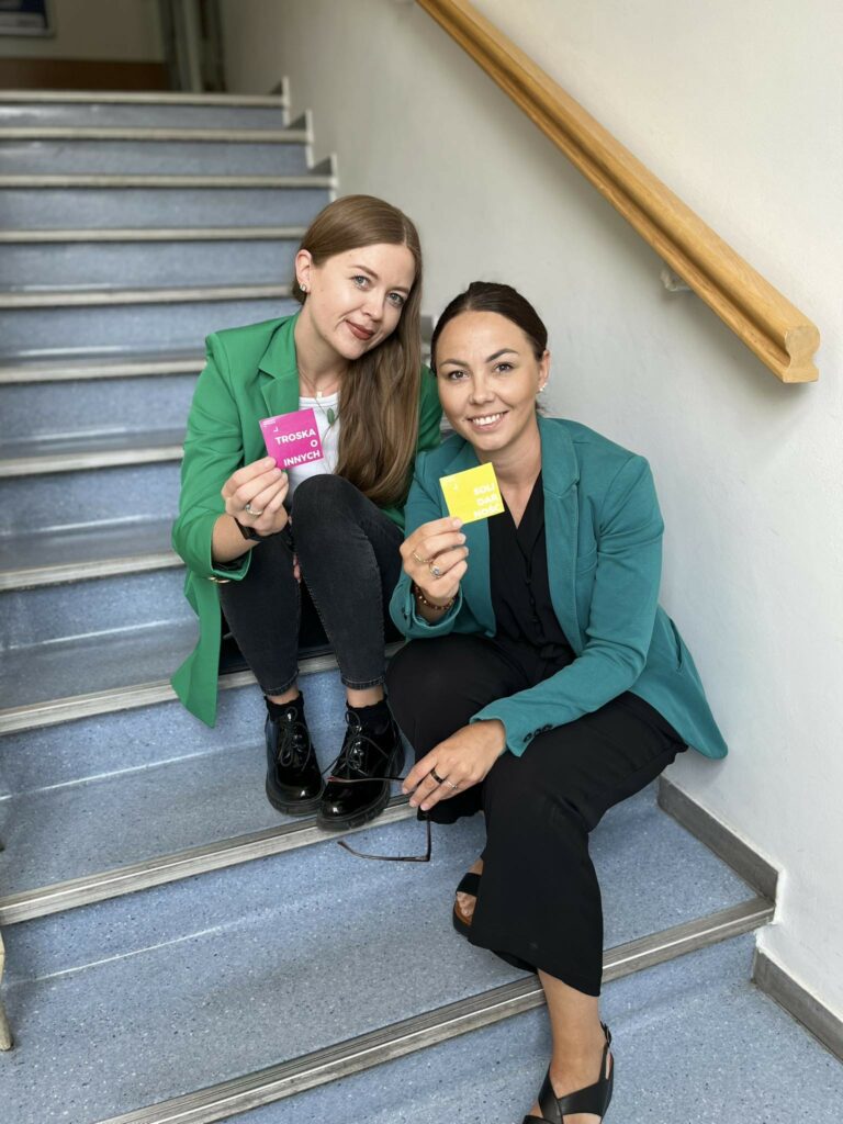 Założycielki Fundacji Powerfly podczas spotkania, siedzące na schodach i uśmiechające się do aparatu